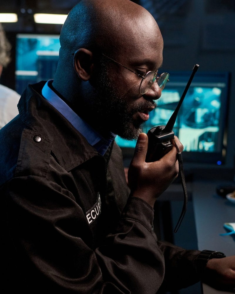 Security officer using a two-way radio in a camera monitoring room